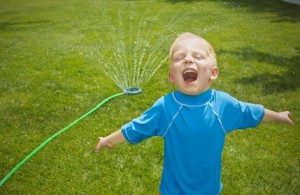 Young boy playing in the sprinklers outdoors